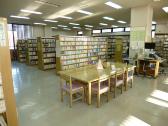 沢山の本が棚に並べられ、机と椅子が設置されている新習志野図書館一般書コーナー室内の写真
