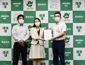 松丸委員長代理、吉田委員長が宮本市長へ報告書を手渡ししている写真