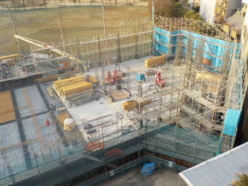建物の周囲に足場が組まれ、資材が積まれている建設中の建物の1階部分の写真