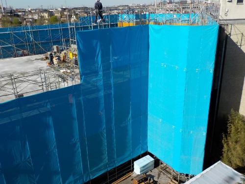 建物の周囲の足場の外側を水色のシートで囲んでいる写真