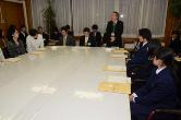 大きな白いテーブルの奥に立ち開式の言葉を述べている経営改革推進室長の写真