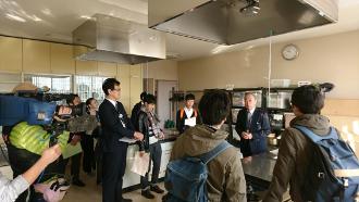 スーツ姿の男性から調理室内で説明を受ける参加者の写真