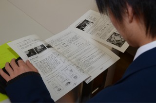 男子学生がレクチャーノートを読んでいる様子の写真