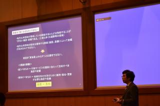 資料が映し出された画面の右側で話をしている男性の写真