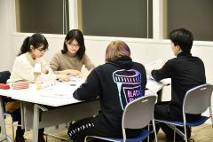 4名の参加者がテーブルに向かい合って座り話し合っている様子の写真