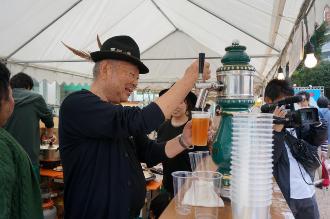 黒色のハットを被った男性が笑顔でビールをついでいる写真