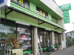 2階建て黄緑の外観の「マルキ金物専門店」の写真