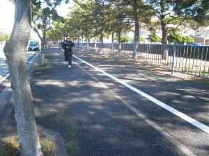 街路樹が植えられた歩道を走っている天野真一さんの写真