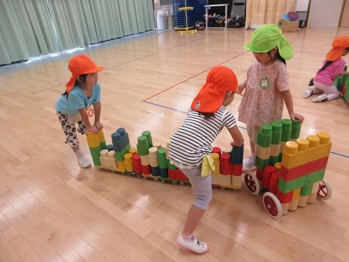 5歳児と4歳児がBブロックで作った乗り物に乗って遊んでいる所