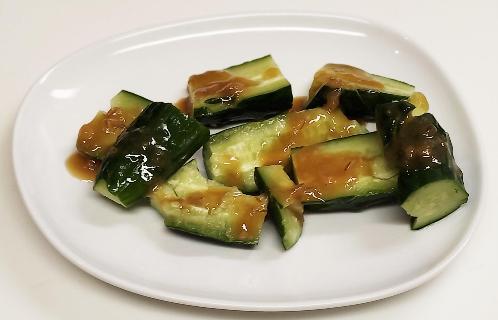 白いお皿の上に縦半分に切ってぶつ切りして叩いたキュウリにまぶされた味噌