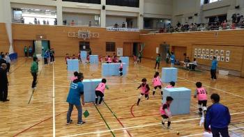 ピンク色のゼッケンをつけた子供達が柔らかいボールを使って、すぽーつゆきがっせんを行っている体育館内の様子の写真