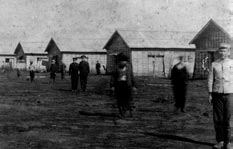 間隔をあけて兵士が立っており、後方には建物が写っている白黒写真