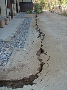 道路の地表面に亀裂や陥没が起こっている写真