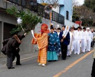御榊を手にした天狗面を先頭に青色の衣装を着た宮司や白色の衣装を着た人々が並んで歩いている八剱神社祭礼「剣」の写真