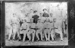 前列の椅子に座っている数名の男性と、後列に立っている数名の男性の白黒集合写真