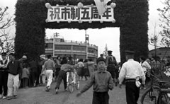 祝市制 五周年と書かれた入場門を行き交う人々の白黒写真