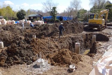 油圧ショベルなどを使い庭園の土に穴を掘ったり、杭頭処理や改修工事などを行っている作業員の写真