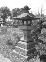 木々や植木に囲まれた場所にある石灯籠の白黒写真
