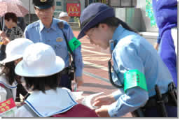 警察官の人がJR津田沼駅で啓発キャンペーンをしている写真