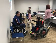 車いすに乗って補助犬と触れ合っている男の子の写真