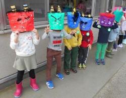 自分で作った鬼のお面を被って横一列に並んでいる子供たちの写真