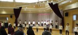 間隔をあけて横2列にならんでいる子供たちが歌を歌っている写真
