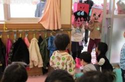 部屋の入り口のドアに鬼の面を被った子供達と室内にいる乳児組の子どもたちの写真