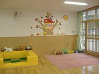 絨毯が敷かれたスペースや大きなクッションで囲まれたスペースがある一時保育室の写真