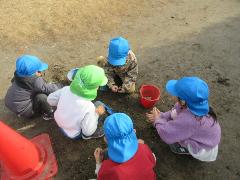 幼稚園と保育所の5歳児が園庭で一緒に砂場遊びをして楽しいんでいる
