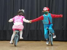 男の子と女の子が手を繋ぎ一輪車に乗っているチャレンジショーの様子の写真