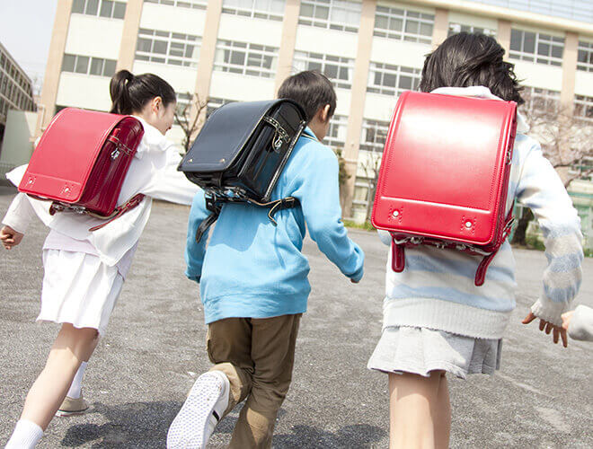 ランドセルを背負い小学校へ走る、女の子2人と男の子1人の画像