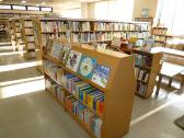 手前の低い本棚に本がぎっしりと並べられた新習志野図書館児童書コーナーの写真
