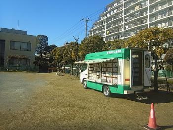 谷津公民館前に横向きに停まっている移動図書館の車の開いたドアからたくさんの本が見えている写真