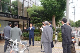 現地視察にて、宮本市長がジェスチャーを交えて話をしており、視察に訪れた関係者が話を聞いている様子の写真