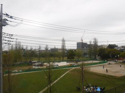 緑色の柵の中に車両が入り仮設駐車場の建設を行っている様子の写真