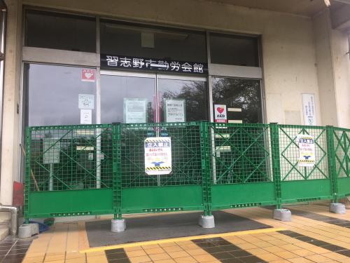 緑色の柵が設置された閉館した勤労会館の入り口の写真