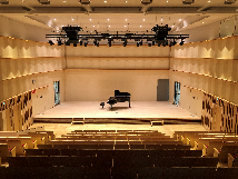 舞台上にグランドピアノが置かれている市民ホールの観客席の後方から撮影した写真（生涯学習複合施設「プラッツ習志野」ページへのリンク）