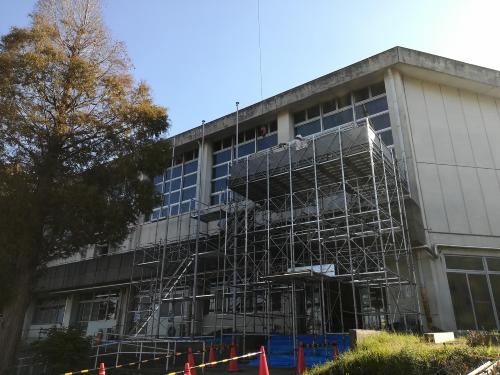 改修工事の建物の周りに足場を組んでいる途中の様子の写真