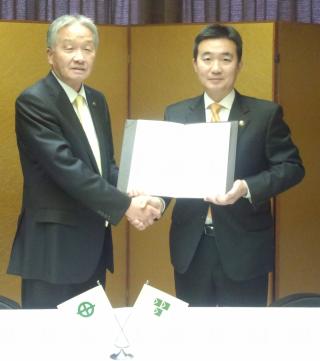 市長が協定書を持ち京田辺市長と握手を交わしている写真