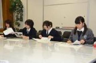 女子高校生の隊員が大きな白いテーブルに並んで座っている学習会の様子の写真