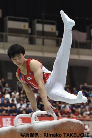 あん馬の台の上で真っ直ぐに左足をあげ演技をしている萱選手の写真