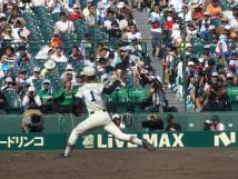 マウンドからボールを投げる体制のユニフォームを着たピッチャー飯塚選手の写真