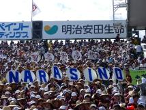 満員の観客席で「NARASINO」と書かれたボードを掲げ応援している様子の写真