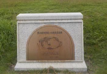 草むらの中に設置されている東経140度線通過標記念碑の写真(茜浜緑地のページへリンク)