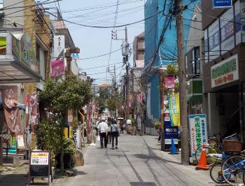 両サイドに店舗が並んでいる間の細い道路を人々が歩いている谷津遊路商店街の写真