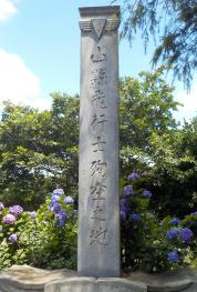 紫陽花の花をバックに縦書きで「山縣飛行士殉空之地」と書かれた石碑の写真