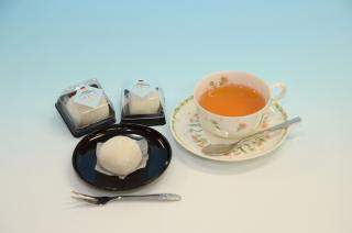 レアチーズ大福2個、黒い器に乗ったレアチーズ大福、紅茶の写真