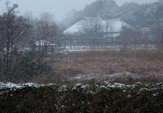 雪が屋根に積もる旧鴇田家住宅を遠くから撮影した写真