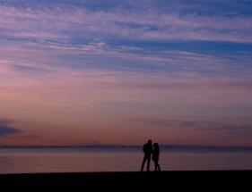 夕暮れに茜浜で撮影された海を背景に二人の人が佇んでいる様子の写真