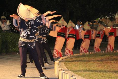 津田沼一丁目公園で夜に法被や浴衣に笠を被った沢山の人が踊りを行っている様子の写真